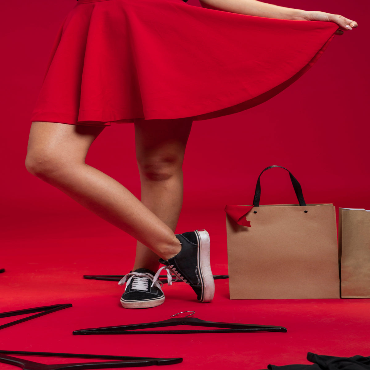 Mujer con falda roja y tenis negros posando en estudio con bolsas de papel ropa femenina de moda México