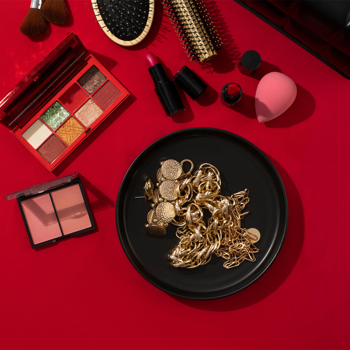 Accesorios de moda para mujer con joyería dorada y maquillaje sobre fondo rojo elegante